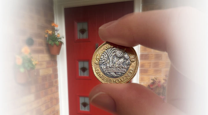 Coin between fingers in front of red composite door